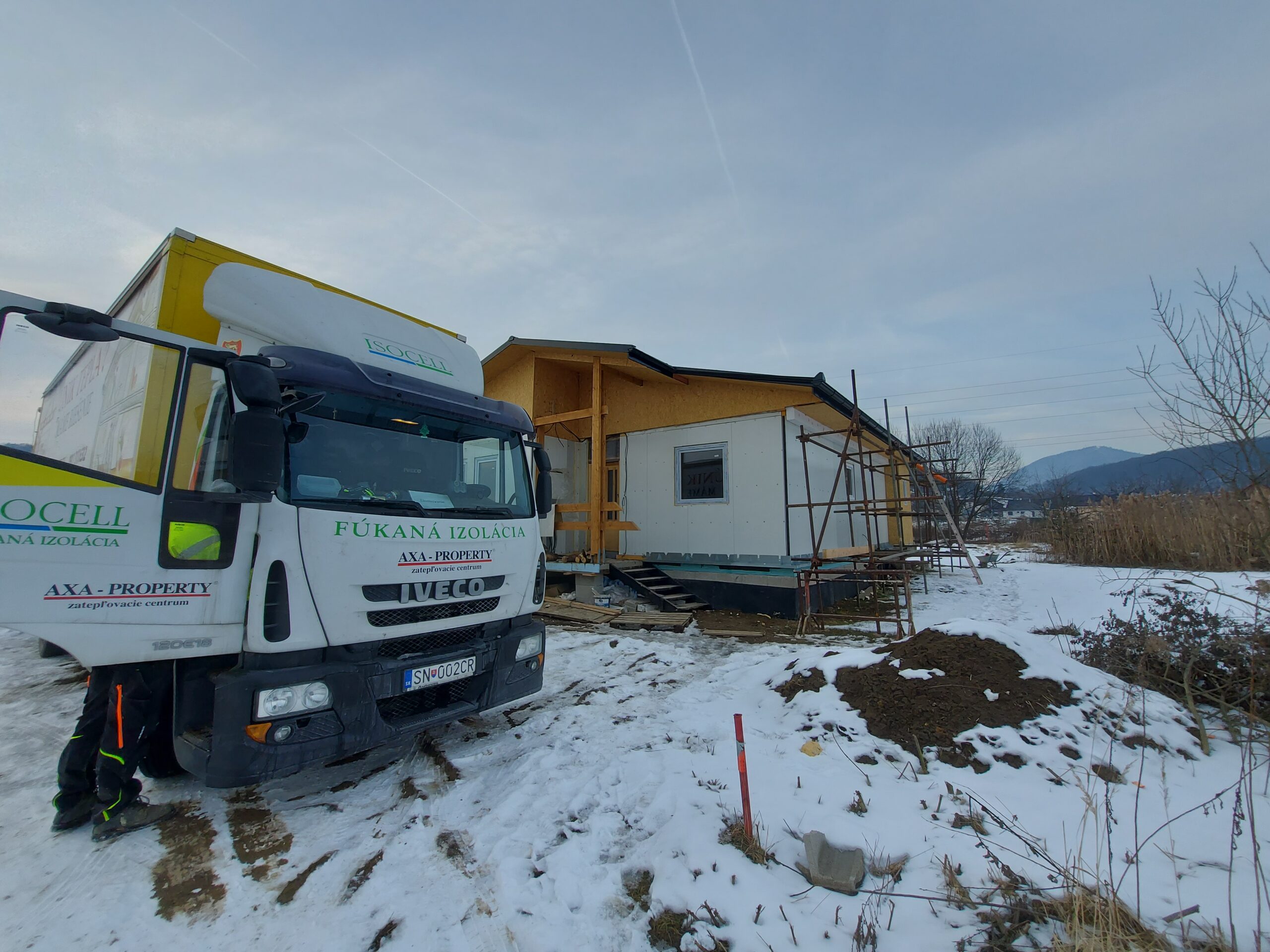 Fúkaná izolácia od spoločnosti AXA Property pri zatepľovaní drevostavby v zimných podmienkach. Pohľad na auto s technológiou fúkanej izolácie 
